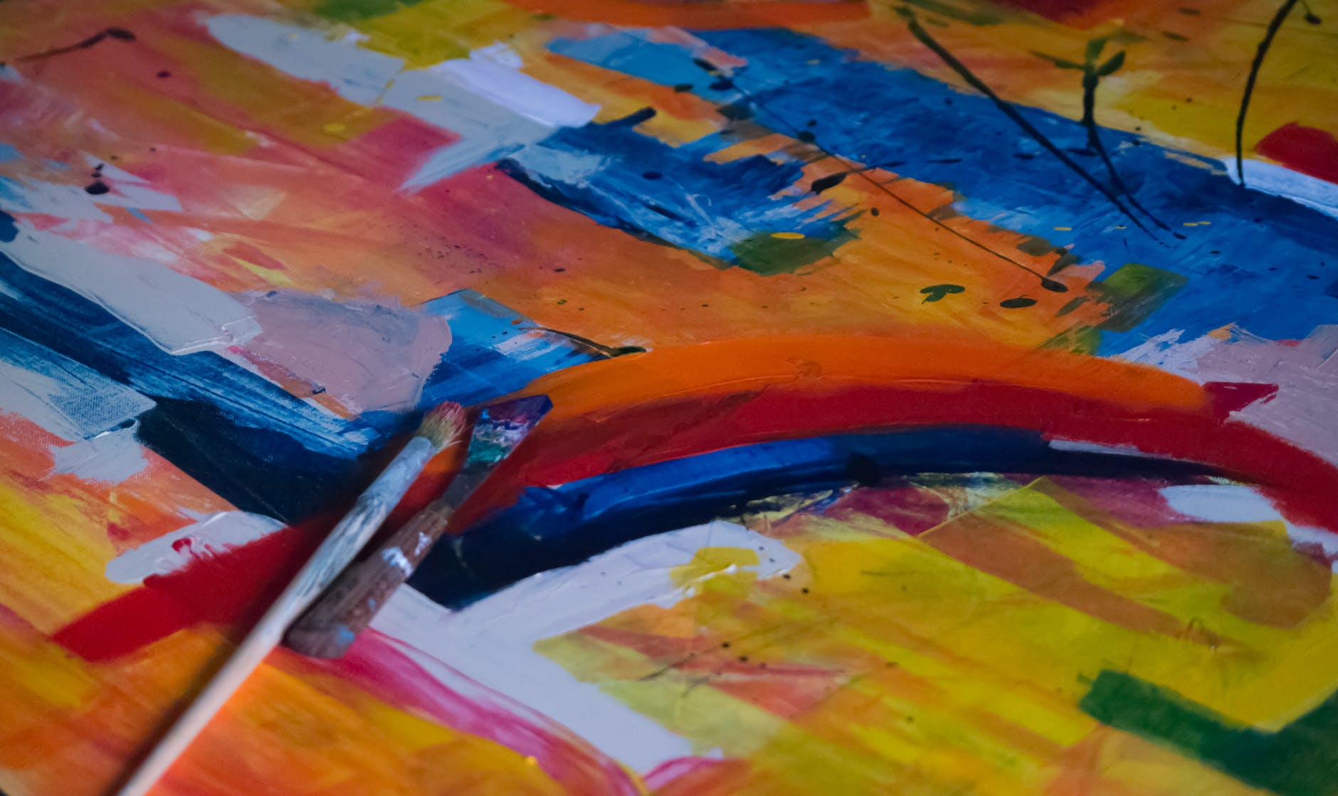 two paintbrushes on multicolored abstract painting